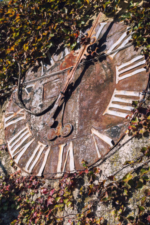 Old vintage rusty clock face with roman numerals, selective focus