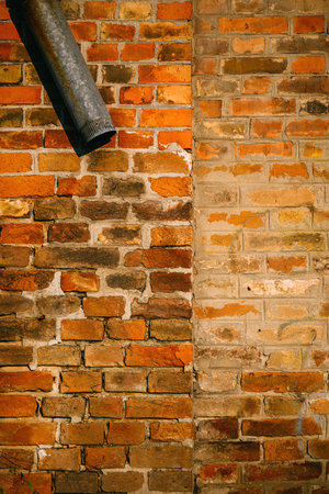 Old worn rain gutter tube against brick wall with copy space
