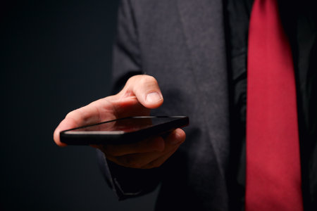 Businessman using smart phone for text messaging, closeup of hand with selective focusの写真素材