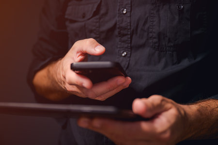 Data synchronization, man using smartphone and digital tablet computer to sync data, selective focus