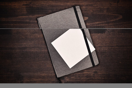 Blank white square shaped note paper on notebook as mockup copy space, top viewの写真素材