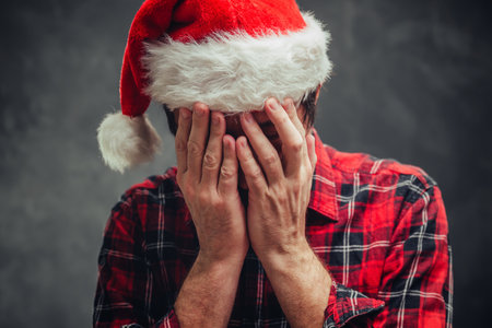 Depressed man during Christmas and New Year holiday wearing Santa Claus hat, selective focusの写真素材