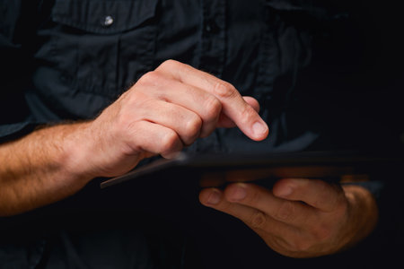 Man using digital tablet computer, low key with selective focus