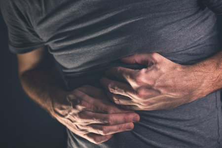 Abdominal pain, man with severe stomachache pressing the belly with his hands, selective focusの写真素材