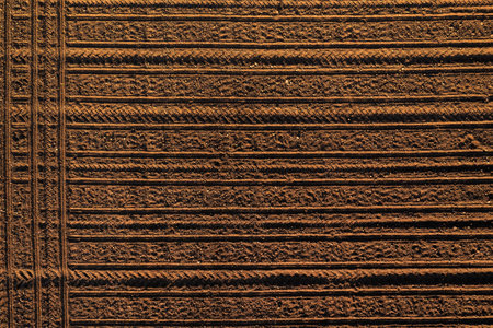Tractor tread marks forming forming pattern in plowed field soil, aerial shot from drone pov, top downの写真素材