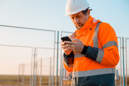 Drilling rig engineer using mobile phone while supervising the process of oil and gas, monitoring...