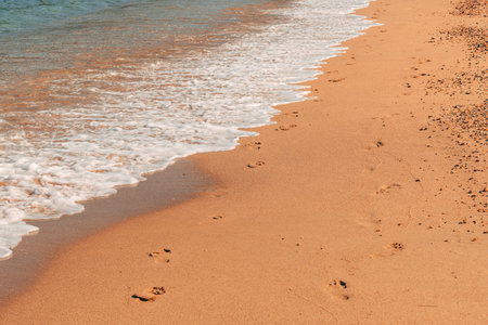 Sea foam washing human footstep in wet beach sand in summer, holiday and vacation by the sea background, selective focusの写真素材