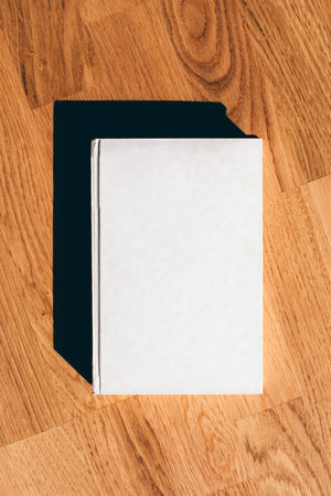 Hardcover book mockup, white blank book cover on hardwood flooring as design template, top view