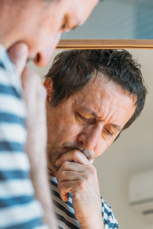 Worried concerned man in front of the mirror, selective focus