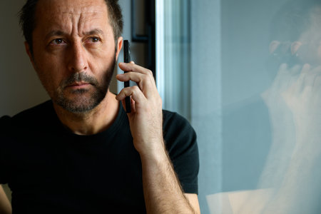 Man talking on mobile phone by the apartment window, selective focus