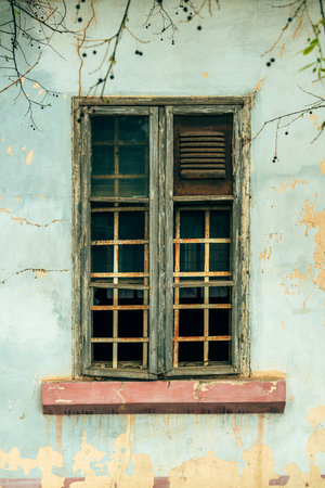 Old broken wooden window of an ruined house, vertical imageの写真素材