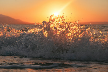 Ocean wave breaking with a beautiful sunrise in background, selective focusの写真素材