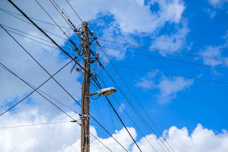 Old wooden lamp post with street light and messy electrical wires, selective focus