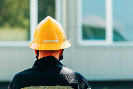 Rear view of male firefighter with yellow protective hard hat helmet, selective focusの写真素材