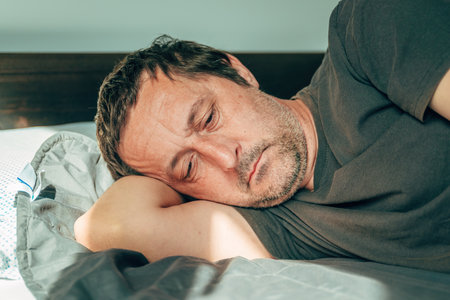 Morning depression and lethargy, portrait of mature adult male laying in bed, selective focusの写真素材