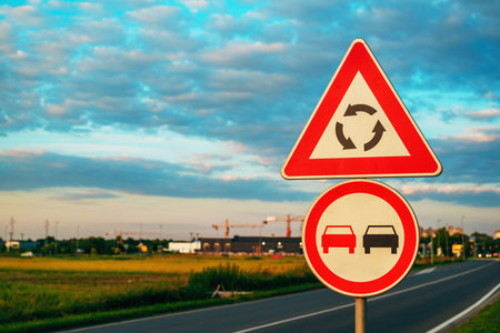 Roundabout ahead and no overtaking traffic signs by the road, selective focusの写真素材