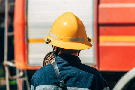 Rear view of male firefighter with yellow protective hard hat helmet, selective focus