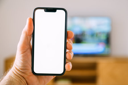 Smartphone mockup screen, man holding mobile phone in front of smart TV television set, tv remote...