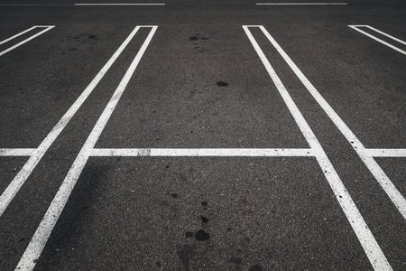 Parking lot, road marking white lines on asphalt surface as abstract pattern, selective focus