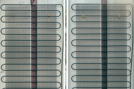 Metal grid condenser coils on refrigerator back panel, showing industrial structure and functional cooling system detail, close upの写真素材