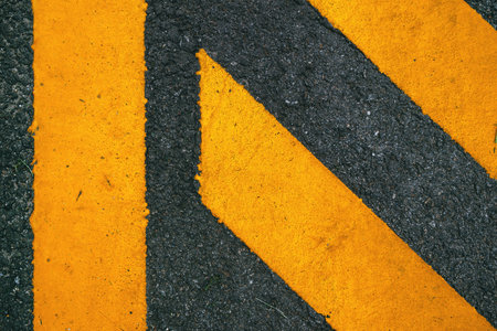 Yellow painted road marking on asphalt surface, urban traffic symbol background. Top view.の写真素材