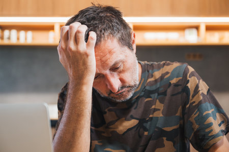 Portrait of depressed mature adult male wearing camouflage army shirt, concept of military war veteran, selective focusの写真素材
