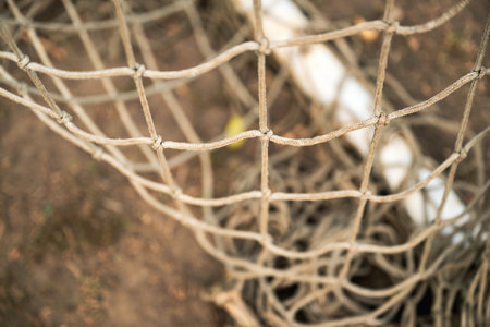 Close-up of old worn soccer goal netting showing frayed fibers and weathered texture. Selective focus.の写真素材