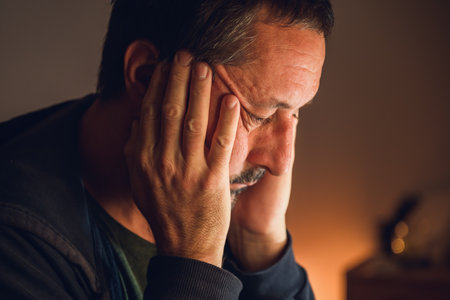 Low key portrait of a mature man in despair, illuminated by soft warm light, symbolizing hopelessness and inner conflict. Selective focus.の写真素材