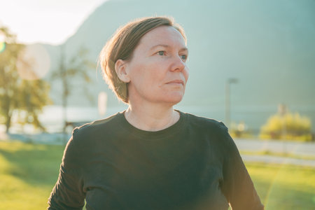 Portrait of a woman outdoors in soft sunset light, symbolizing mindfulness, resilience, and inner strength. Selective focus.の写真素材