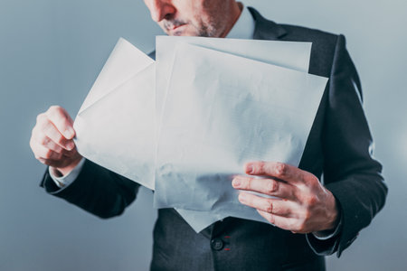 Businessman examining confidential documents with serious expression, selective focusの写真素材