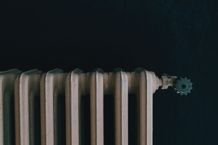 Vintage cast iron radiator with valve detail in dark room, selective focus