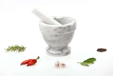A traditional marble mortar and pestle with various herbs and spice isolated on white backgroundの写真素材