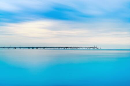 Industrial pier on the sea horizon  Long exposure photography in a cloudy day の写真素材