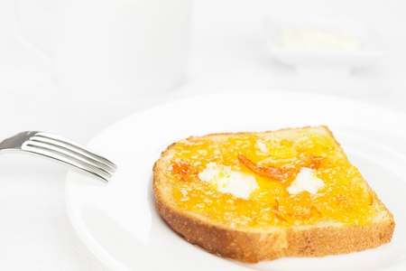 Breakfast  French toast with spread bitter orange marmalade or jam with candied peel, butter curls,...