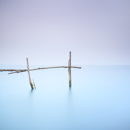 Fishing poles for clams and mussels and soft water on a quiet foggy landscape  Long exposure photographyの写真素材