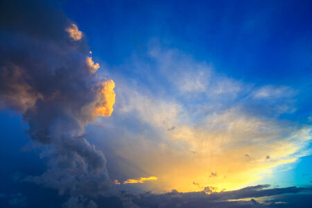 Dramatic sunset sky with yellow, blue and orange approaching thunderstorm clouds の写真素材