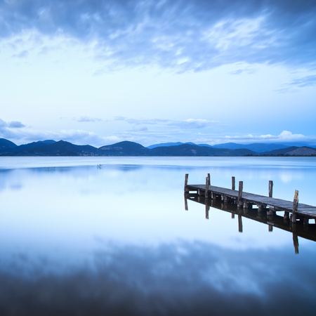 Wooden pier or jetty and on a blue lake sunset and cloudy sky reflection on water  Long exposure, Versilia Massaciuccoli Lake, Tuscany, Italy の写真素材