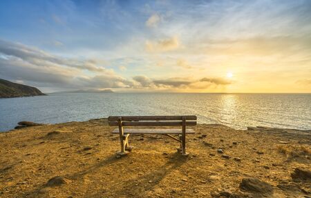 Bench in Populonia famous cliff Buca delle Fate at sunset. Elba Island on the horizon. Piombino,...
