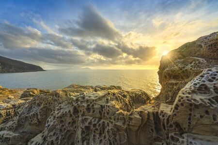 Rocks eroded by the wind and sea in Populonia cliff Buca delle Fate at sunset. Piombino, Maremma Tuscany, Italy.の写真素材