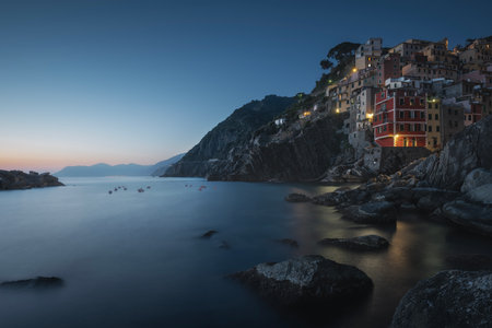 Blue twilight over the fishing village of Riomaggiore. Seascape in Cinque Terre National Park, La Spezia province, Liguria region, Italy, Europe.の写真素材