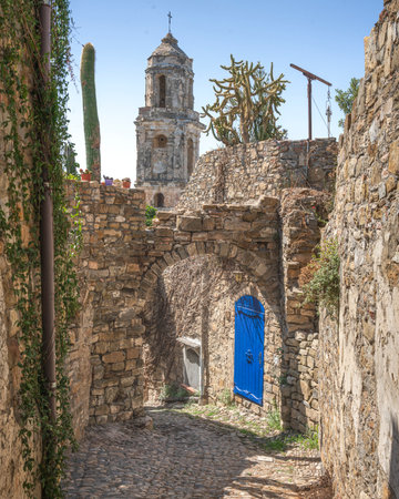Blue door and bell tower view in a street of Bussana Vecchia. Ghost town in Sanremo, Liguria region,...