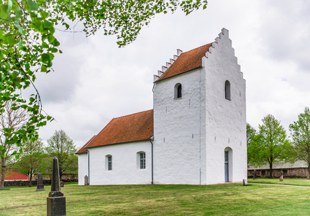 White rural church in the countryside, situated under some trees on a green lawn, Sjobo, Sweden - May 12, 2014の写真素材