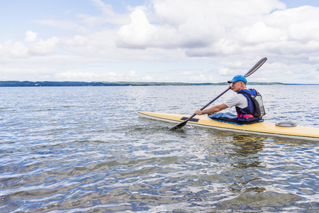 Man is paddling a yellow kayak alone in the bay, Holl, Denmark, August 27, 2017のeditorial素材