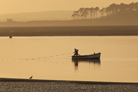 A fisherman hauling in his nets on the coast near Caernarfon in Gwynedd in Wales.のeditorial素材