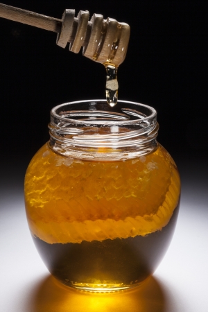 A jar of Comb Honey with part of a honeycomb in the jar の写真素材