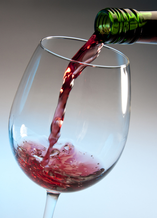 Pouring red wine into a glassの写真素材