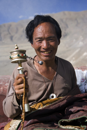 A Buddhist pilgrim spinning a prayer wheel on a hilltop near Yambulagang Palace in the Tibet Autonomous Region of China.のeditorial素材