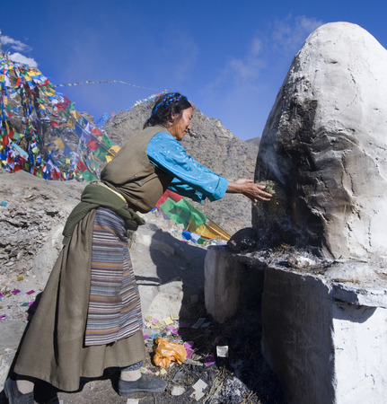 A pilgrim burning incense and Buddhist prayer flags on a hilltop near Yambulagang Palace in the Tibet Autonomous Region of China.のeditorial素材