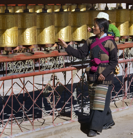 A Buddhist pilgrm turning prayer wheels at the Pelcho Monastery in the town of Gyantse in the Tibet Autonomous Region of China. のeditorial素材