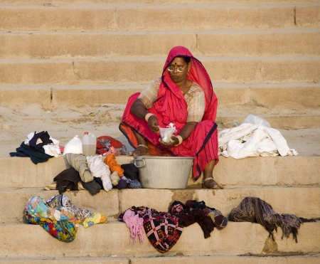 Indian woman washing clothes on the Hindu Ghats by the River Ganges in Varanasi in the Uttar Pradesh region of India.のeditorial素材